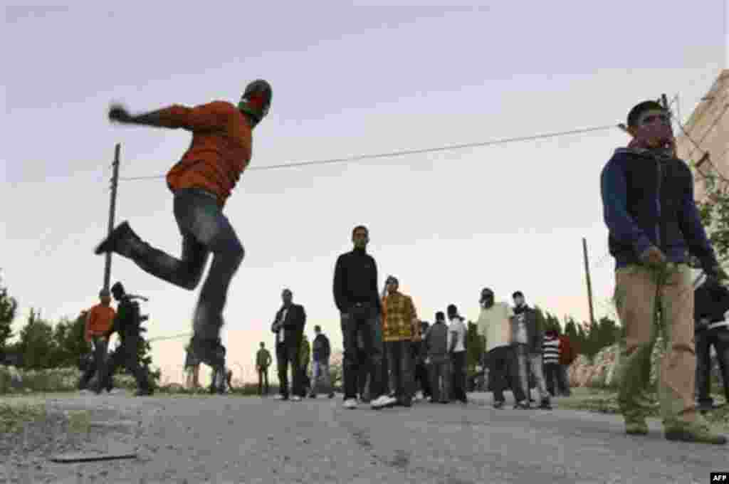 A Palestinian youth throws rocks at Israeli soldiers, not seen, during a protest against an Israeli roadblock at the entrance to the West Bank village of Beitin, near Ramallah, Monday, Dec. 27, 2010. (AP Photo/Majdi Mohammed)