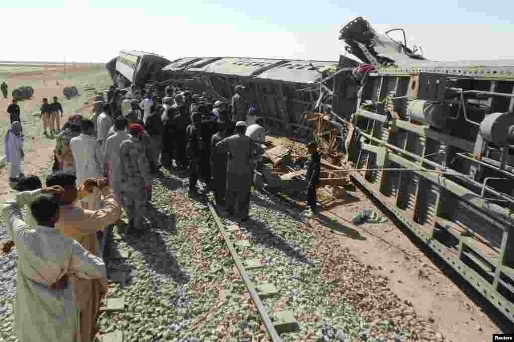 Officials, rescue workers and residents gather near the passenger train derailed after it was hit by a bomb attack in Dera Murad Jamali, located in the Nasirabad District of Balochistan province, Pakistan.