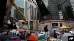 A man walks some tents set up by pro-democracy protesters in an occupied area outside government headquarters in Hong Kong's Admiralty district, Nov. 13, 2014.