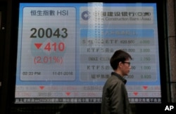 A man walks past an electronic board showing Hong Kong share index outside a local bank in Hong Kong, Jan. 11, 2016.