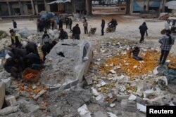People collect scattered oranges amidst rubble after an airstrike on a market in rebel-held Maarat Mastrin in Idlib province, Syria, Jan. 14, 2017.