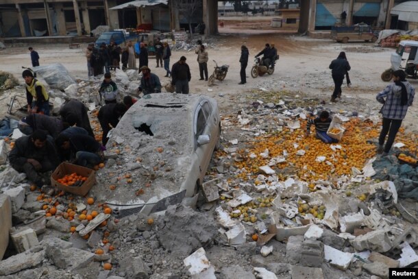 People collect scattered oranges amidst rubble after an airstrike on a market in rebel-held Maarat Mastrin in Idlib province, Syria, Jan. 14, 2017.