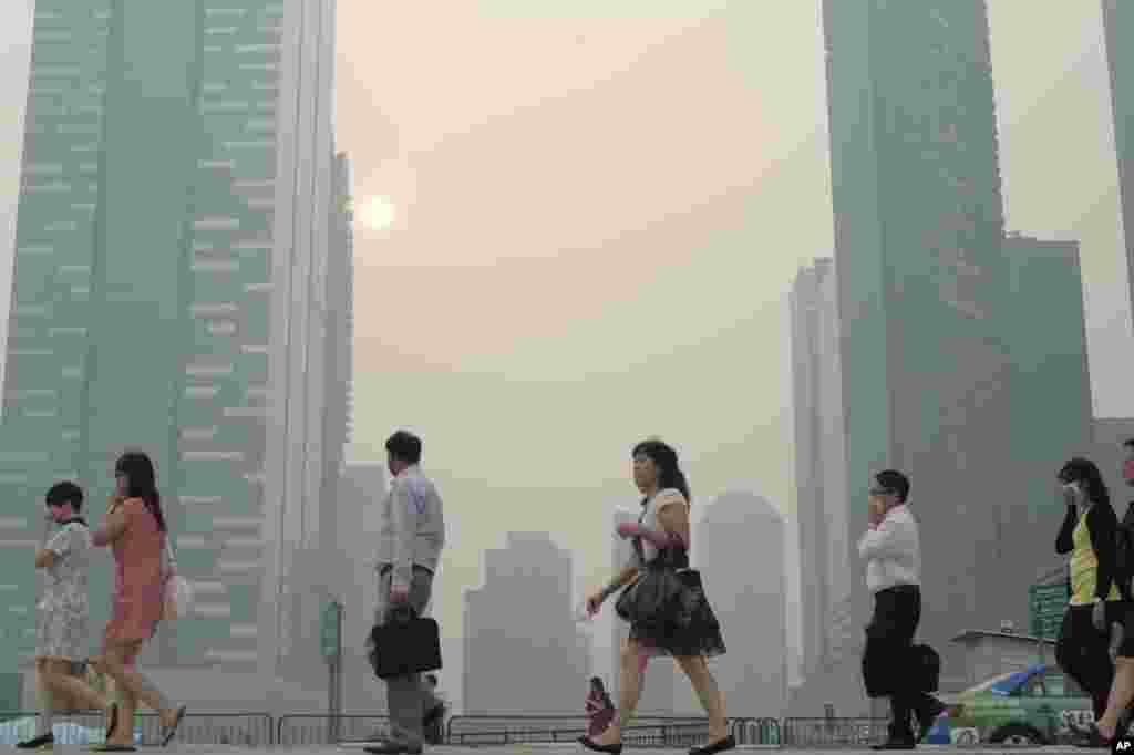 Office workers walk through a haze blanketing the Singapore Central Business District, June 20, 2013.