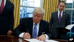도널드 트럼프 미국 대통령(가운데)이 지난 1월
백악관 집무실에서 경제 관련 행정명령에 서명하고 있다. (자료사진)