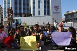 FILE - Demonstrators display signs during a protest against the suspension of teachers from classrooms over purported links with Kurdish militants in Diyarbakir, Turkey, Sept. 19, 2016.