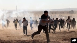 Turkish security forces use teargas and water cannons to disperse protesting local people as several hundred Syrian refugees wait at the border, in Suruc, Turkey, Sept. 21, 2014.