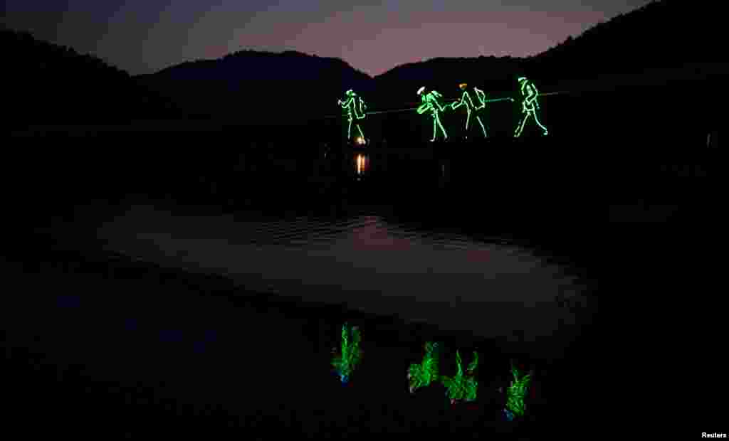 Tourists wearing LED-lit costumes walk on their way for a drifting tour at an eco-park in Changsha, Hunan province, China, Aug. 23, 2015.