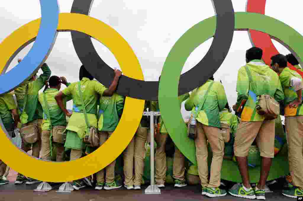 Volunteers pose for a photograph with a set of Olympic Rings inside Olympic Park in Rio de Janeiro, Brazil.