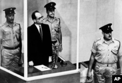 FILE - Adolf Eichmann is seen standing in his glass cage, flanked by guards, in the Jerusalem courtroom during his trial in 1961 for war crimes committed during World War II.