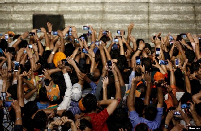 Supporters of Indian Prime Minister Narendra Modi use their mobile phones to take his picture as he addresses them after the election results at the Bharatiya Janata Party (BJP) headquarter in New Delhi, India, May 23, 2019.