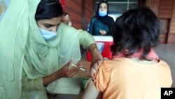 FILE - A woman receives the Pfizer COVID-19 vaccine from a health worker at a vaccination center in Islamabad, Pakistan, Oct. 4, 2021.