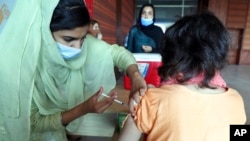 FILE - A woman receives the Pfizer COVID-19 vaccine from a health worker at a vaccination center in Islamabad, Pakistan, Oct. 4, 2021.
