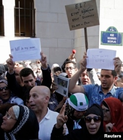 Muslims holding signs saying "not in my name" gather in front of the Paris Mosque after Friday prayers Sept. 26, 2014 to pay tribute to Herve Gourdel, a French mountain guide who was beheaded by an Algerian Islamist group, and to protest extremist tactics