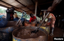A young artisanal miner washes crushed rock containing gold in metal drums at the unlicensed mining site of Nsuaem Top in Ghana, Nov. 23, 2018.