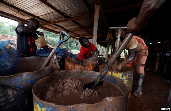A young artisanal miner washes crushed rock containing gold in metal drums at the unlicensed mining site of Nsuaem Top in Ghana, Nov. 23, 2018.
