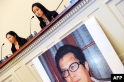 中国维权律师郭飞雄的妻子张青（左）和女儿杨天娇在参加美国国会听证会前举行记者会，讲台前有郭飞雄的照片（2013年10月29日）