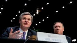 FBI Director Christopher Wray, accompanied by CIA Director Mike Pompeo, right, speaks at a Senate Select Committee on Intelligence hearing on worldwide threats, in Washington, Feb. 13, 2018. 