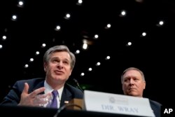 FBI Director Christopher Wray, accompanied by CIA Director Mike Pompeo, right, speaks at a Senate Select Committee on Intelligence hearing on worldwide threats, in Washington, Feb. 13, 2018.