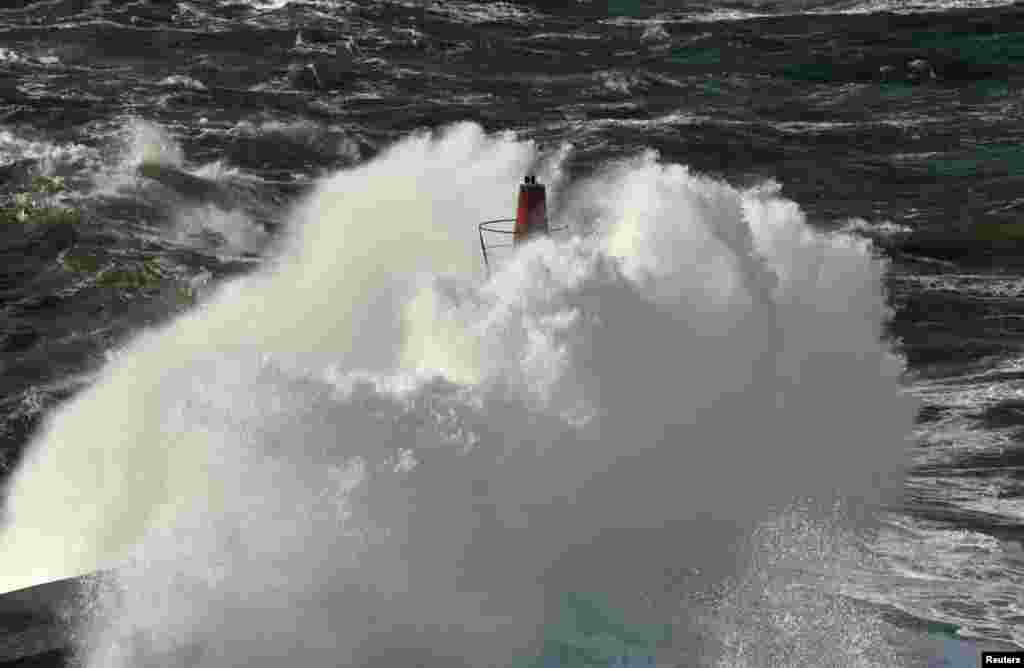 Waves crash against a lighthouse on the Viavelez seafront in the northern Spanish region of Asturias.