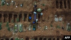 Pogrebni radnici sahranjuju telo čoveka koji je navodno preminuo od kovida 19, na groblju u Vila Formosi, u predgrađu Sao Paula, Brazil, 22. maja 2020. (Photo by NELSON ALMEIDA / AFP)