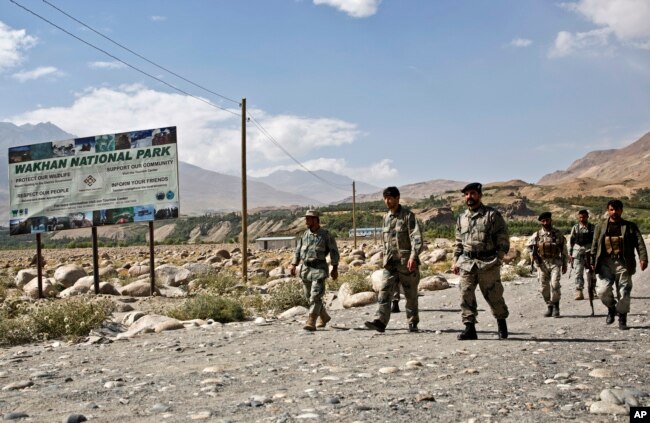 FILE - Afghan border police walk the Afghanistan side of the border with Tajikistan, in Ishkashim, Badakhshan province, far northeastern Afghanistan, Aug. 16, 2016.