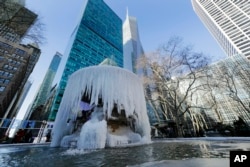 Pedestrians pass a frozen water fountain at Bryant Park, Jan. 31, 2019, in New York.