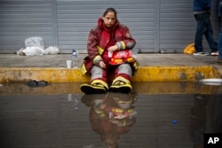 In this June 23, 2017, photo, exhausted firefighter Julia Alegre Smith rests after battling a warehouse fire in Lima, Peru.