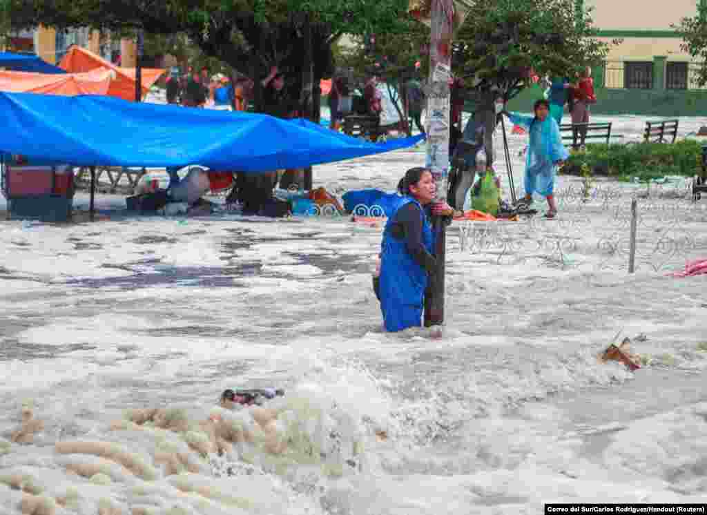 A woman clings to a lamp post during flooding caused by heavy rains in Sucre, Bolivia, Jan. 4, 2021.