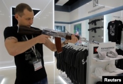 A salesperson demonstrates a model AK-47 assault rifle at the newly opened Gunmaker Kalashnikov souvenir store in Moscow's Sheremetyevo airport, Russia, August 22, 2016.