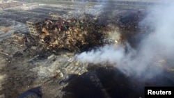 An aerial picture shows smoke rising from the debris among shipping containers at the site of last week's explosions at Binhai new district in Tianjin, China, Aug. 15, 2015. 