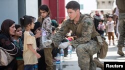 Seorang Marinir AS dengan 24th Marine Expeditionary Unit (MEU) memberikan air kepada seorang anak selama evakuasi di Bandara Internasional Hamid Karzai, Kabul, Afghanistan, 20 Agustus 2021. (Foto: Sersan Samuel Ruiz/Korps Marinir AS via Reuters)