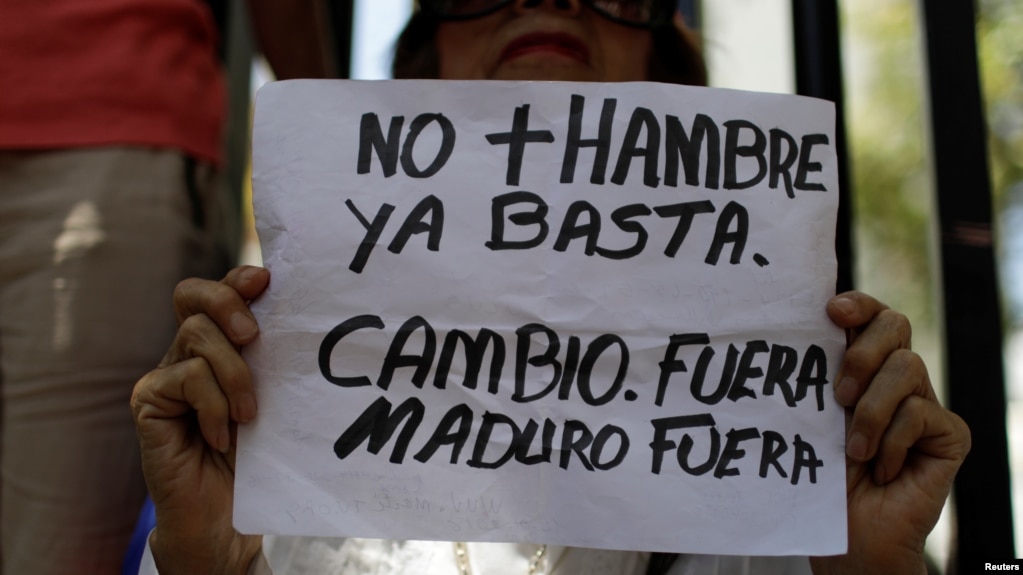 Una opositora del gobierno de Nicolás Maduro sostiene un cartel de protesta pidiendo el cambio de gobierno en Venezuela. Caracas, marzo 17, de 2018. 