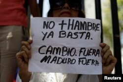 A woman holds a placard that reads "No more hunger. Stop. Change. Out Maduro Out" — a reference to President Nicolas Maduro — during a gathering of opposition supporters in Caracas, Venezuela, March 17, 2018.