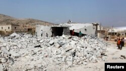 Cư dân gần một tòa nhà bị phá hủy trong các cuộc không kích của Hoa Kỳ và liên minh tại Kfredrian, tỉnh Idlib, Syria, ngày 24/9/2014.