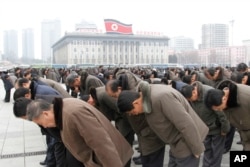People bow to portraits of the late leaders, Kim Il Sung and Kim Jong Il, at the Kim Il Sung Square in Pyongyang, North Korea, Dec. 17, 2016, to mark the fifth anniversary of Kim Jong Il's death.