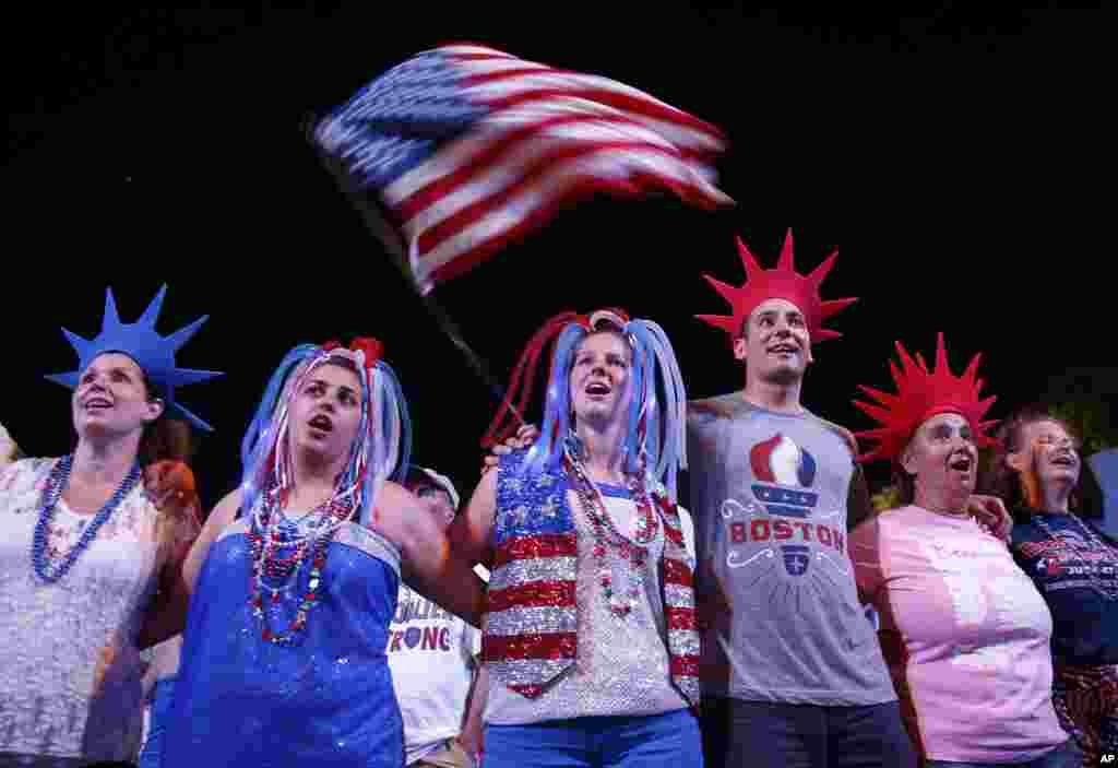 Audience members join arms as the Boston Pops play "God Bless America" during their Fourth of July Concert at the Hatch Shell in Boston, July 4, 2013