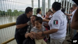 Mama mhamiaji wa Honduras na mtoto wake wakivuka daraja baada ya kuvuka mpaka ulioko kati ya Guatemala and Mexico, katika mji wa Ciudad Hidalgo, Mexico, Octoba 20, 2018.