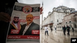 A man holds a poster showing images of Saudi Crown Prince Muhammed bin Salman (L), dubbed "assassin," and of journalist writer Jamal Khashoggi, dubbed "martyr," during a prayer service for Khashoggi, in Istanbul, Turkey, Nov. 16, 2018.