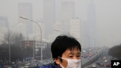 资料照：一名戴着口罩的妇女走在北京人行天桥上。（2015年12月20日）