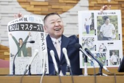 Yasuhiko Abe, who coached golfer Hideki Matsuyama during his Tohoku Fukushi University years, holds special editions of newspapers featuring Matsuyama's Masters victory as he speaks at a press conference in Sendai, Japan April 12, 2021. (Kyodo photo via Reuters)