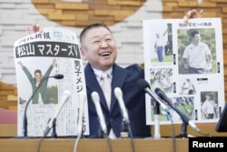 Yasuhiko Abe, who coached golfer Hideki Matsuyama during his Tohoku Fukushi University years, holds special editions of newspapers featuring Matsuyama's Masters victory as he speaks at a press conference in Sendai, Japan April 12, 2021. (Kyodo photo via Reuters)