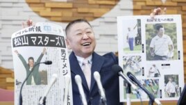 Yasuhiko Abe, who coached golfer Hideki Matsuyama during his Tohoku Fukushi University years, holds special editions of newspapers featuring Matsuyama's Masters victory as he speaks at a press conference in Sendai, Japan April 12, 2021. (Kyodo photo via Reuters)