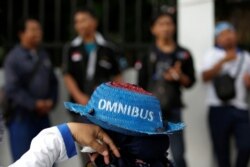 Seorang pekerja mengenakan topi saat mengikut demonstrasi menentang rencana pemerintah merevisi Undang-Undang Ketenagakerjaan, di luar gedung DPR/MPR, Jakarta, 20 Januari 2020. (Foto: Reuters)
