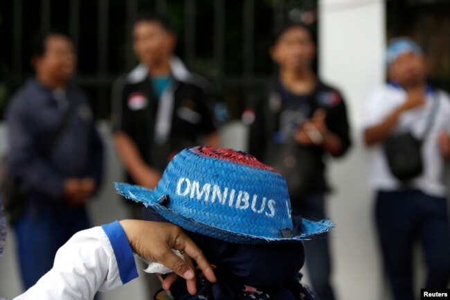 Seorang pekerja mengenakan topi saat mengikut demonstrasi menentang rencana pemerintah merevisi Undang-Undang Ketenagakerjaan, di luar gedung DPR/MPR, Jakarta, 20 Januari 2020. (Foto: Reuters)