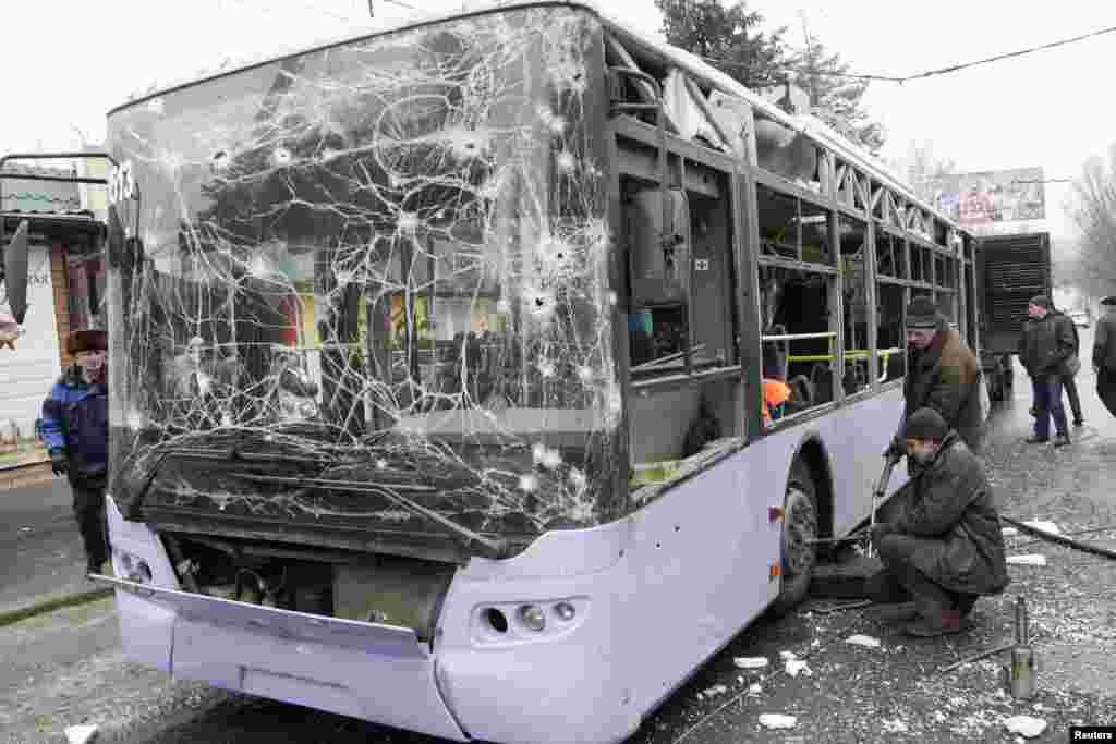 People surround a damaged trolley bus that was shelled, killing at least 13 people, in Donetsk, Ukraine, Jan. 22, 2015. 