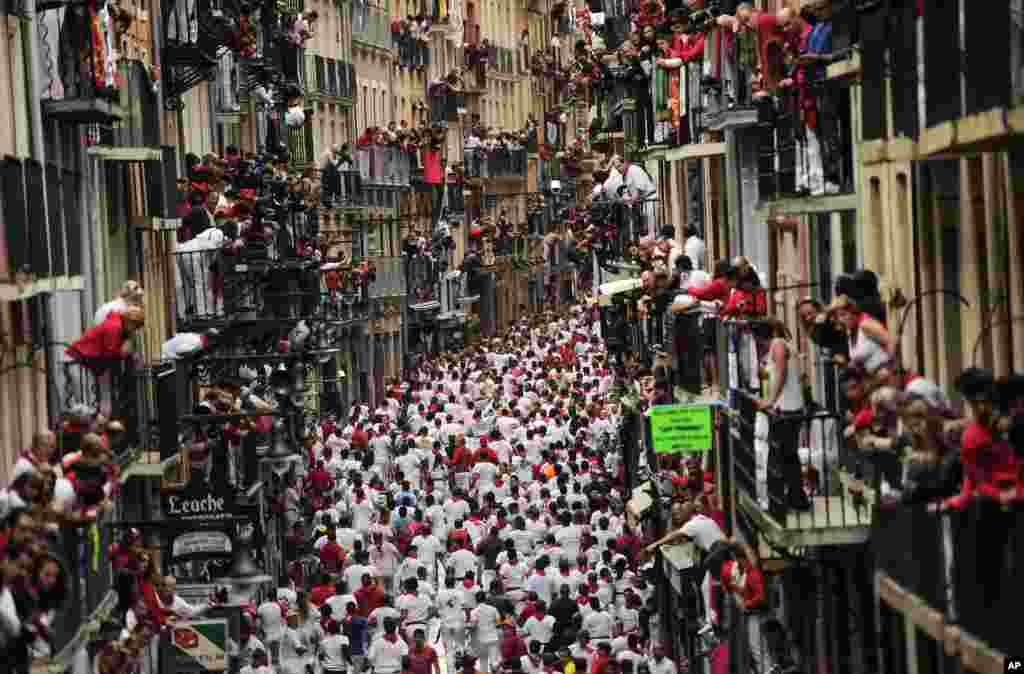 Revelers run on Estafeta Street during the running of the bulls at the San Fermin festival in Pamplona, Spain.