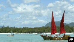 Un bateau mauricien dépasse une réplique du Flor de la Mar, un navire pirate servant d’attraction touriste sur la côte Est de Maurice, 13 novembre 2003.