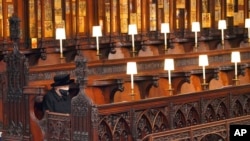 FILE - Britain's Queen Elizabeth II sits alone in St. George's Chapel during the funeral of Prince Philip, her husband of 73 years, at Windsor Castle, Windsor, England, April 17, 2021.