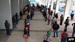 Las personas mantienen su distancia mientras hacen cola en una estación de trolebuses en el norte de Quito, el 3 de junio de 2020, cuando Ecuador comienza a reabrir su economía en medio de la pandemia del nuevo coronavirus COVID-19.