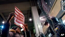 A protester stands facing police officers at an entrance of Terminal 4 at John F. Kennedy International Airport in New York, Jan. 28, 2017, after earlier in the day two Iraqi refugees were detained while trying to enter the country.